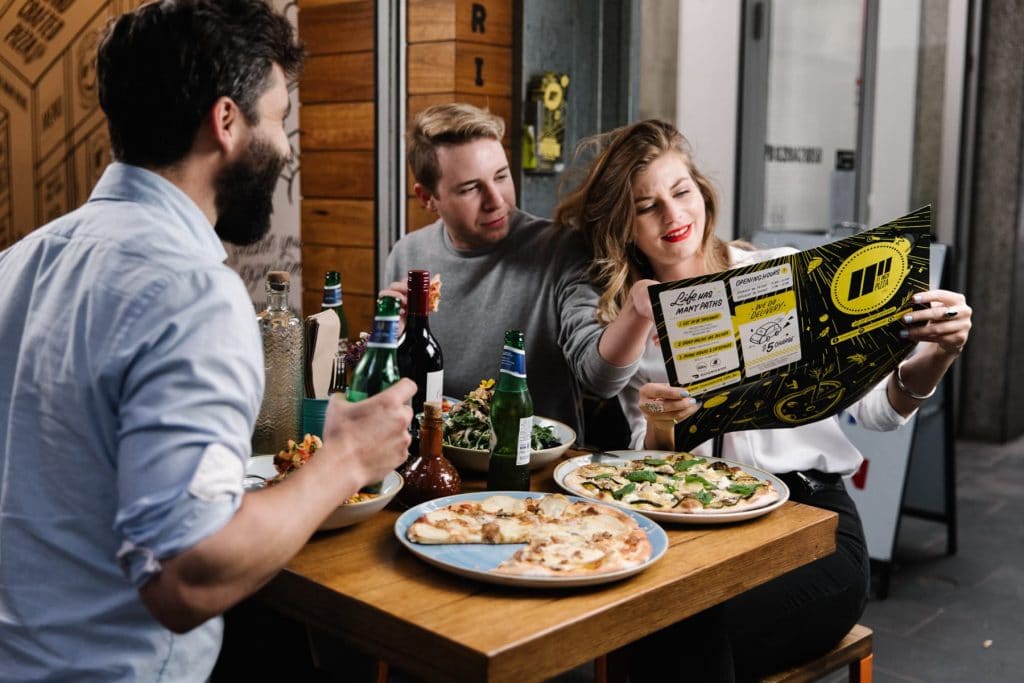 Customers sitting at 11 Inch Pizza reading the pizza menu