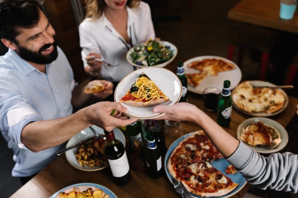 Customers passing a piece of pizza