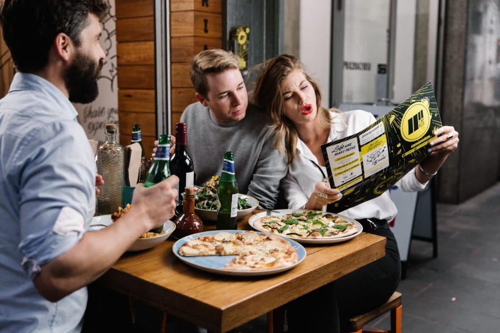 Customers sitting at a table at 11 Inch Pizza, looking at the menu